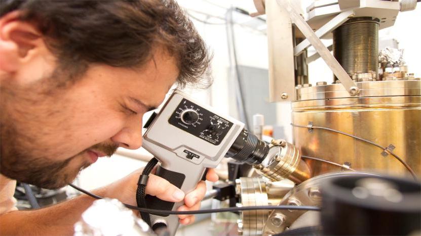 在实验室里使用仪器进行研究的男物理系学生.