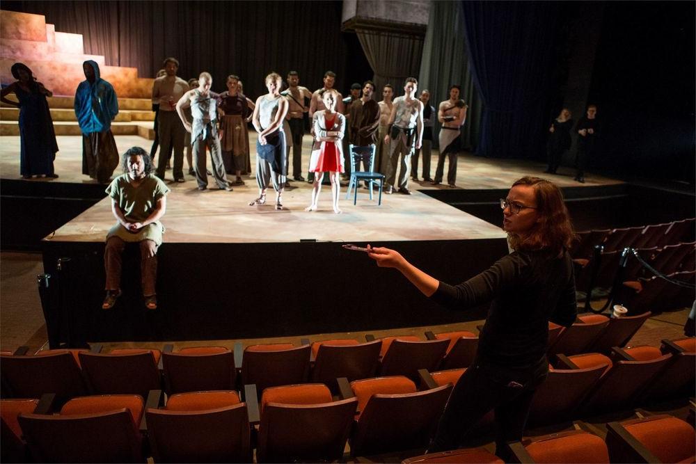 A female student is directing actors on stage.