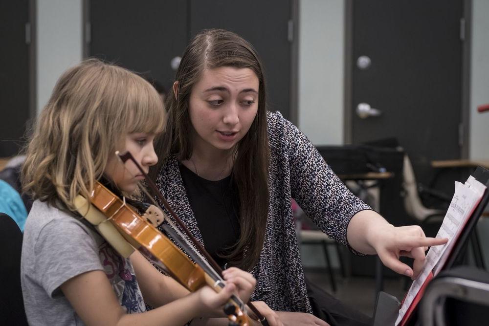 一名PG电子试玩平台APP音乐学生在小提琴课上与一名小学生一起工作.